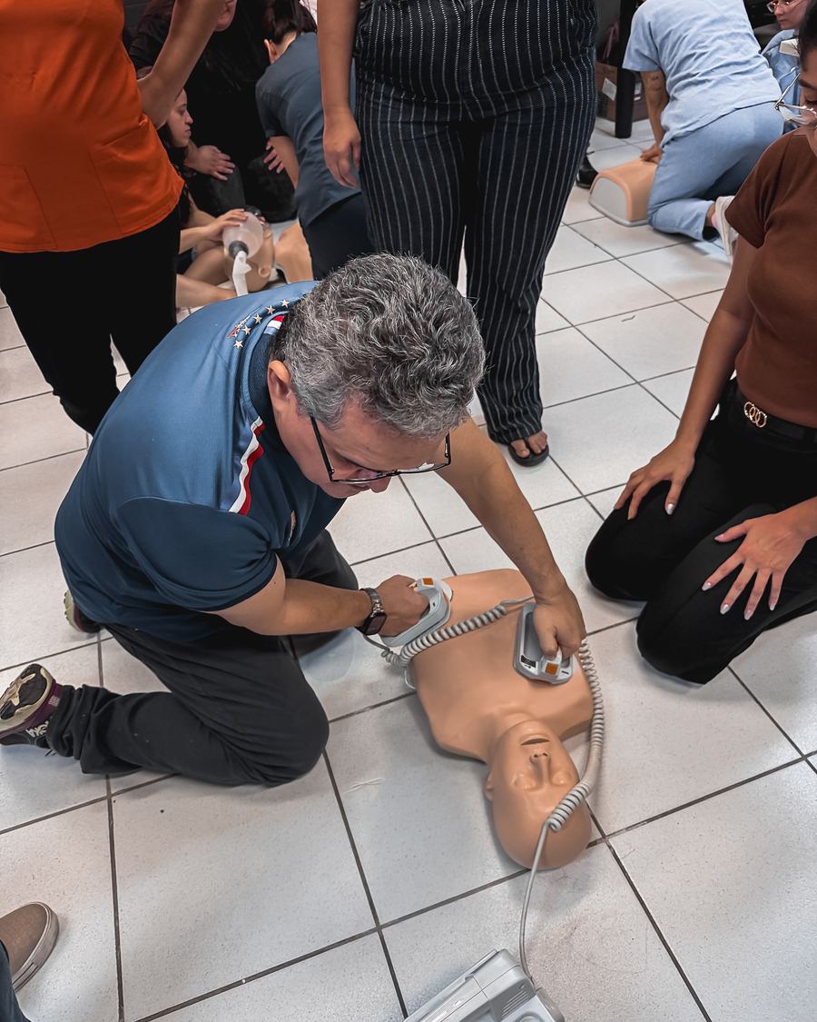 Instrutor demonstra RCP em manequim com alunos ao redor